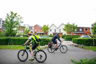 Two cyclists passing each other on a paved cycle route through a housing estate.