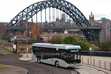 Electric bus in foregraound with the Tyne Bridge dominating the skyline behind.