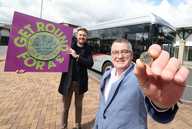Councillor Martin Gannon holds up a pound coin in front of a bus and someone holding a Get Round for a £ poster.