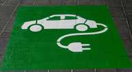 Electric charging point symbol painted on paved surface.